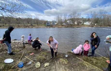 Children enjoying outdoor activities by a lake on a cloudy day.