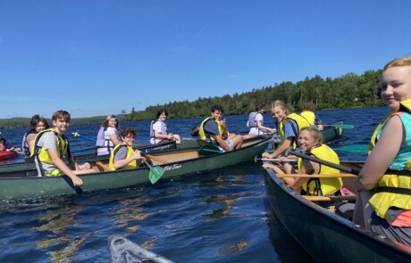 Two rowing boats with people enjoying a sunny day on the water.